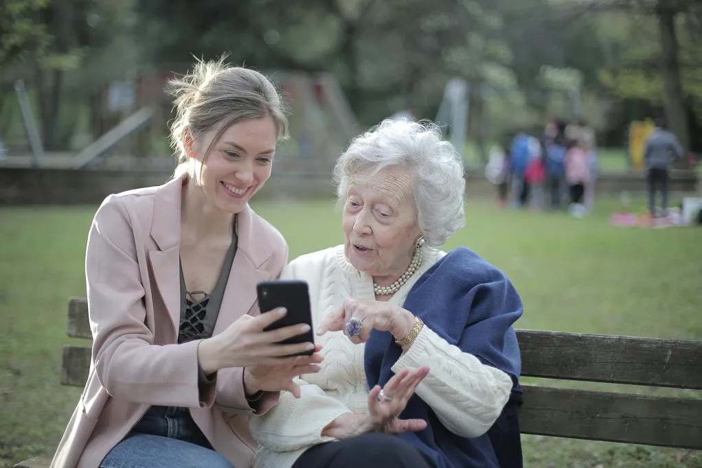 A helper showing a senior how to use her phone.