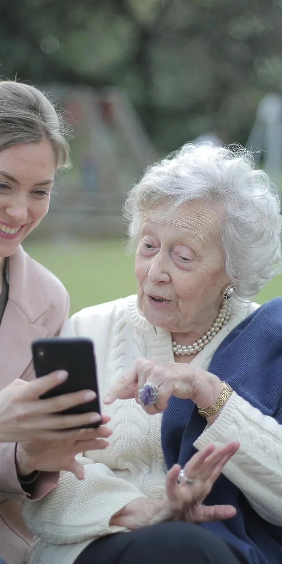 A helper showing a senior how to use her phone.