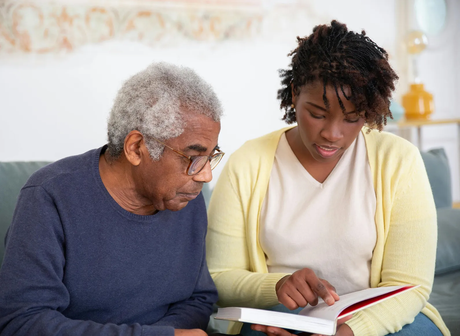 A helper reading a book with a senior