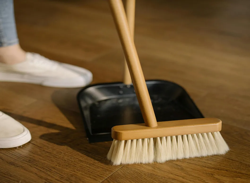 A helper cleaning the floor with a brush