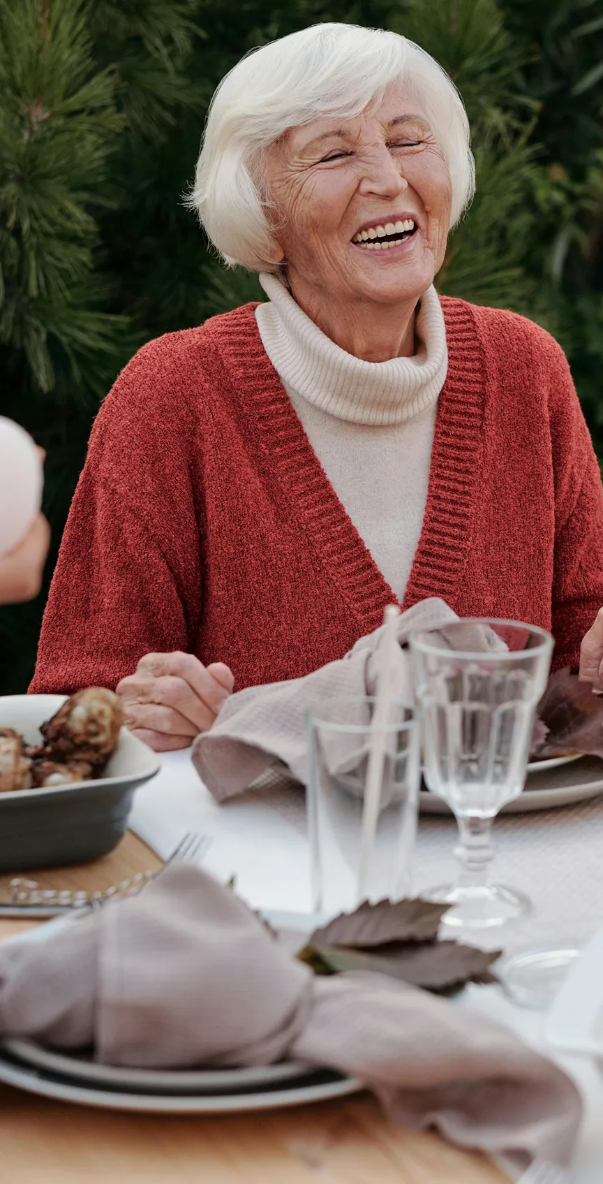 A senior laughing at a dinner party
